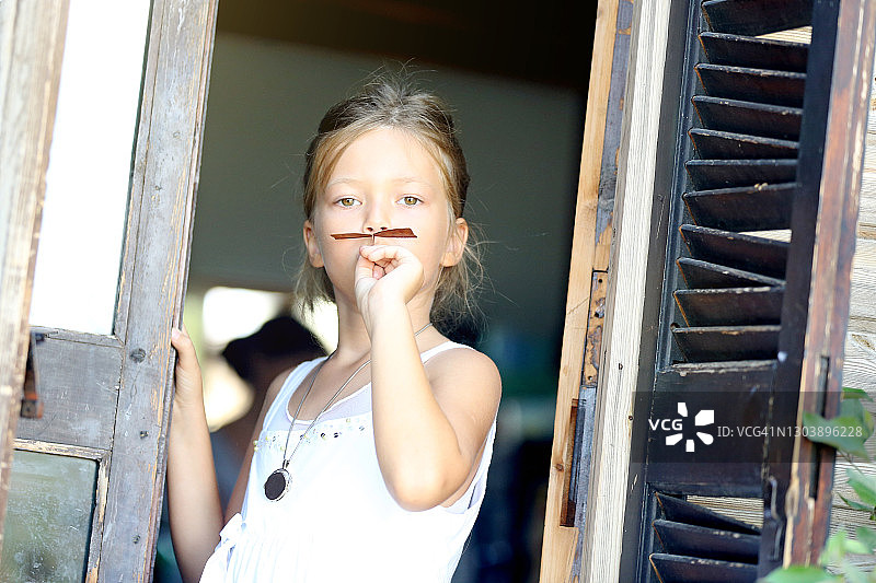 在后院做假胡子的8-9岁漂亮女孩肖像图片素材