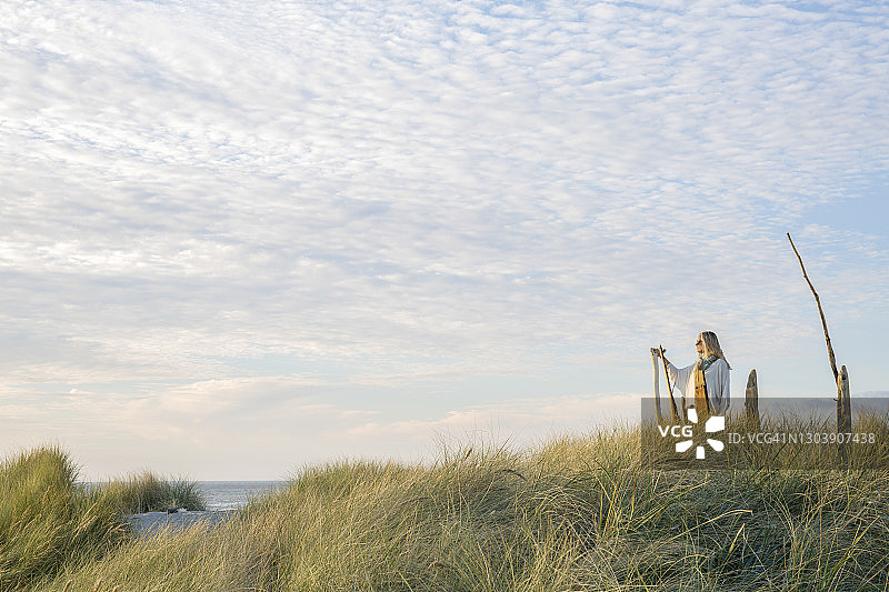 女子在早晨海滩附近的草地上放松图片素材