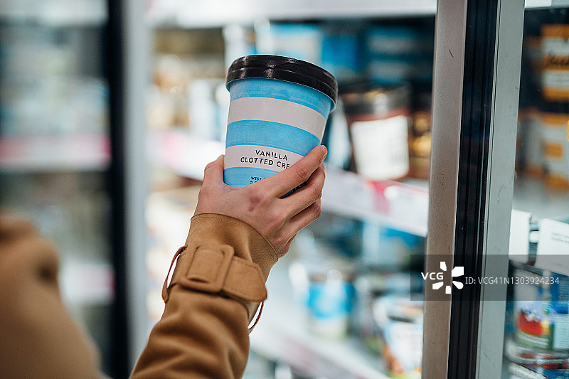 女人在超市里拿着一杯香草冰淇淋的特写镜头图片素材