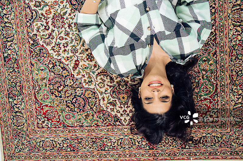 躺在地毯上放松的年轻女人图片素材