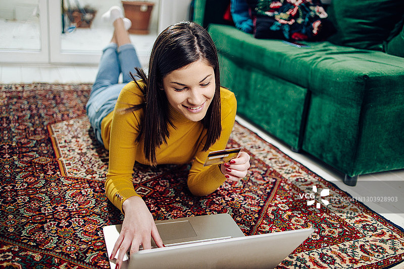 年轻女人在地板上享受网购图片素材