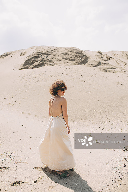 年轻女子身穿露背装在沙漠中行走图片素材