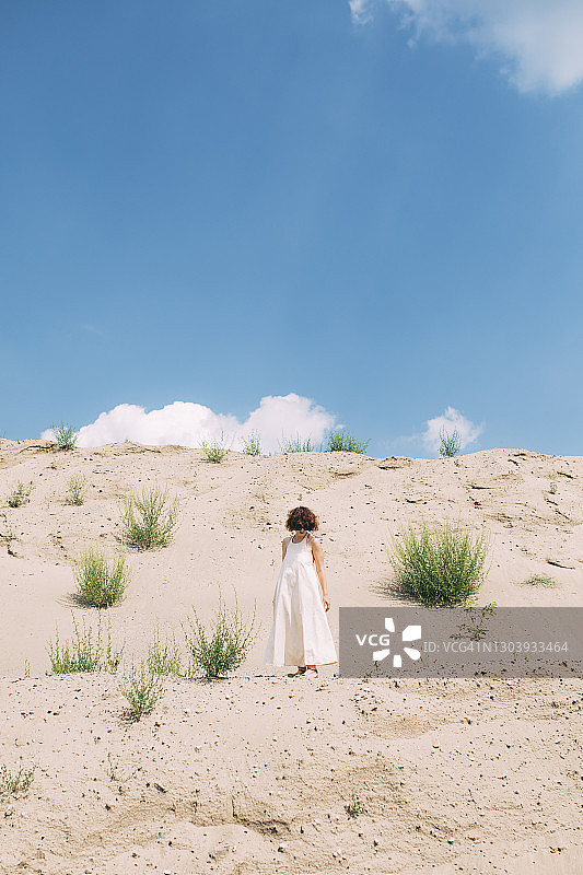 年轻女子身穿露背装在沙漠中行走图片素材