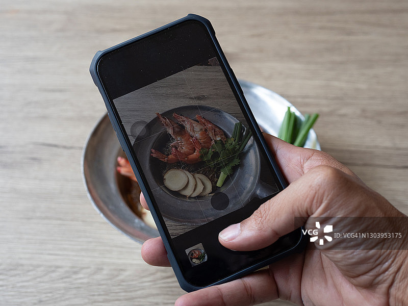 亚洲男人用智能手机拍摄外卖食物图片素材