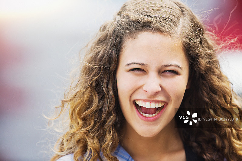 笑容满面，在户外拥有长卷发的年轻美女图片素材