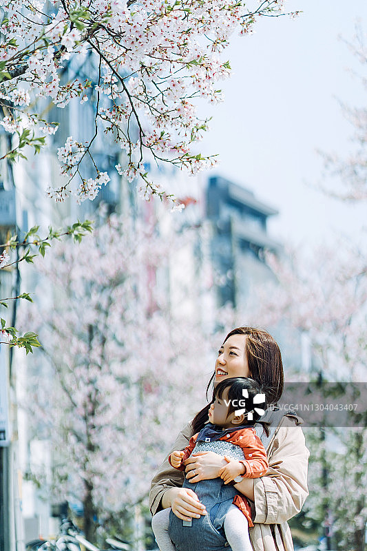 亚洲母亲和女儿在樱花树下享受春天图片素材