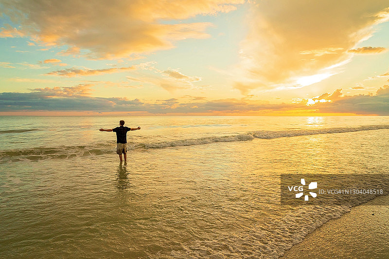 站在海中张开双臂的年轻男子剪影图片素材