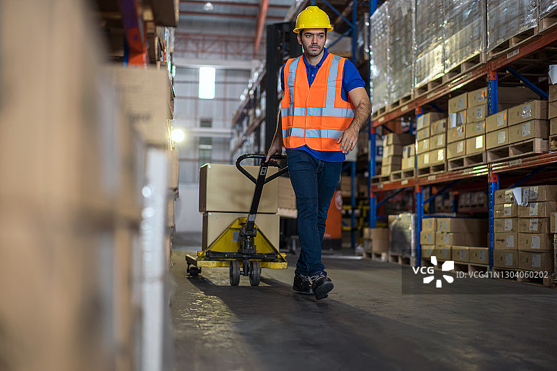 仓库工人使用手动搬运车搬运成品图片素材
