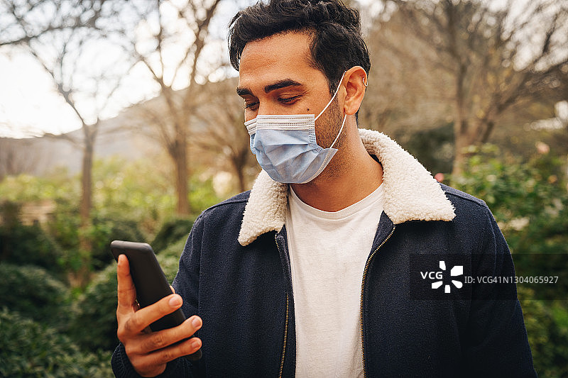 男人戴口罩使用手机的肖像图片素材