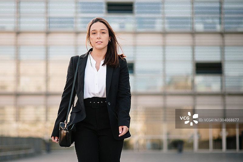 年轻女商人走在办公楼区域图片素材