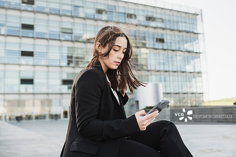坐着并使用智能手机的年轻女商人图片素材