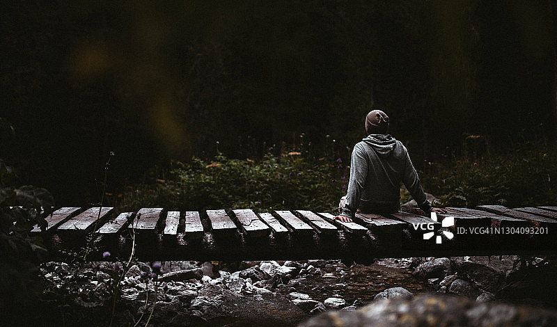 旅行者坐在木桥上看着森林图片素材