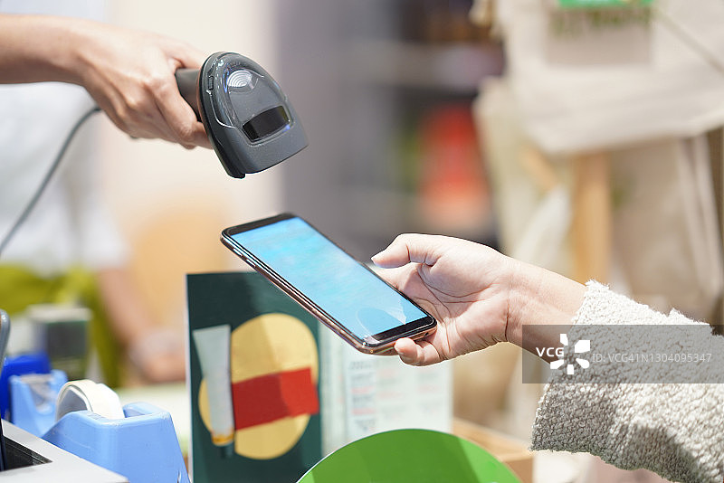零售店扫描客户手机屏幕上的条形码图片素材