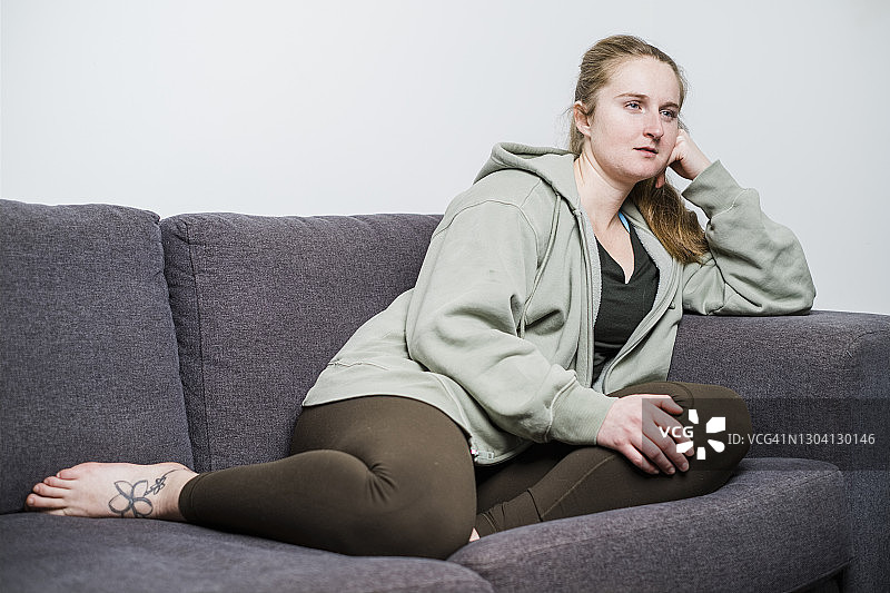 年轻女子穿着舒适的衣服躺在沙发上图片素材