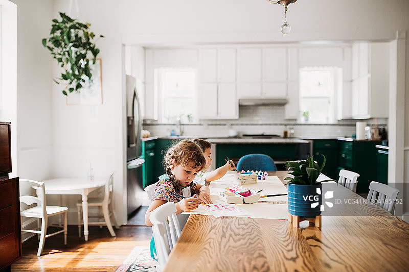 两个小孩子在现代餐厅里做手工图片素材