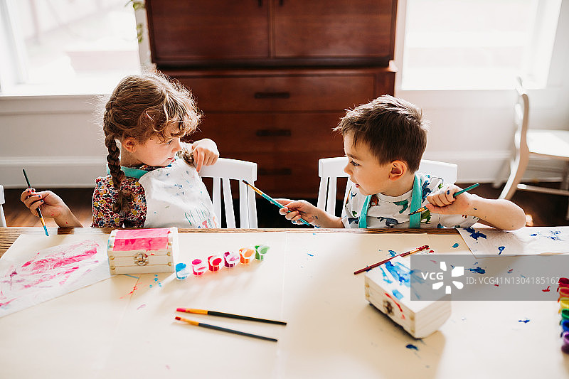 兄妹在桌旁用彩虹颜料绘画图片素材