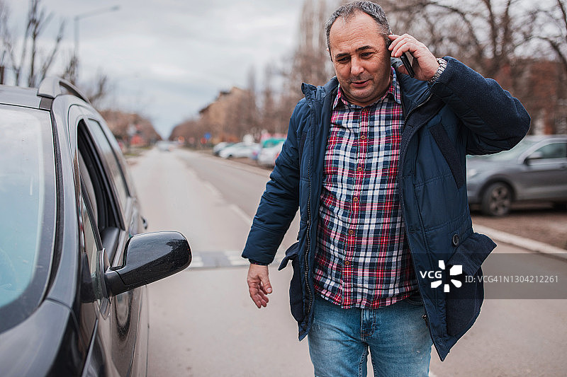 男人站在车旁用智能手机交谈图片素材