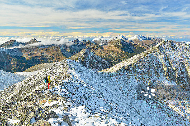 男游客在白雪皑皑的山顶徒步图片素材