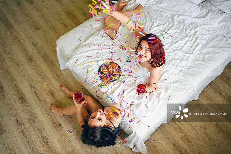 穿着睡衣在床上吃羊角面包的女孩们图片素材