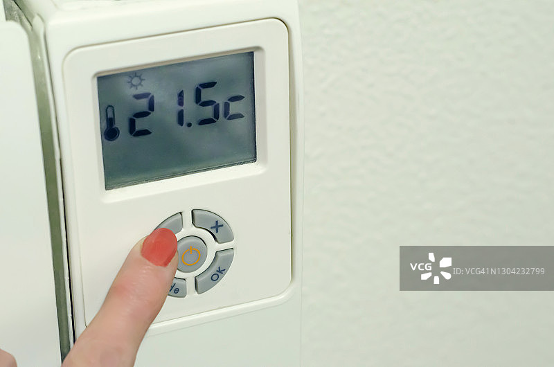 女人在家中按压散热器上数字恒温器按钮的手部特写镜头图片素材