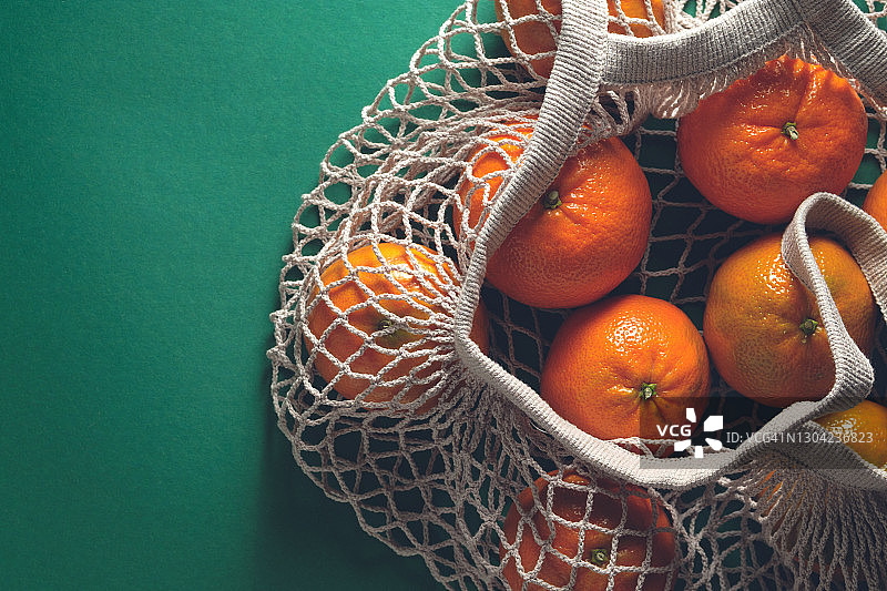 绿色背景下的再生材料环保袋中的未成熟橘子图片素材