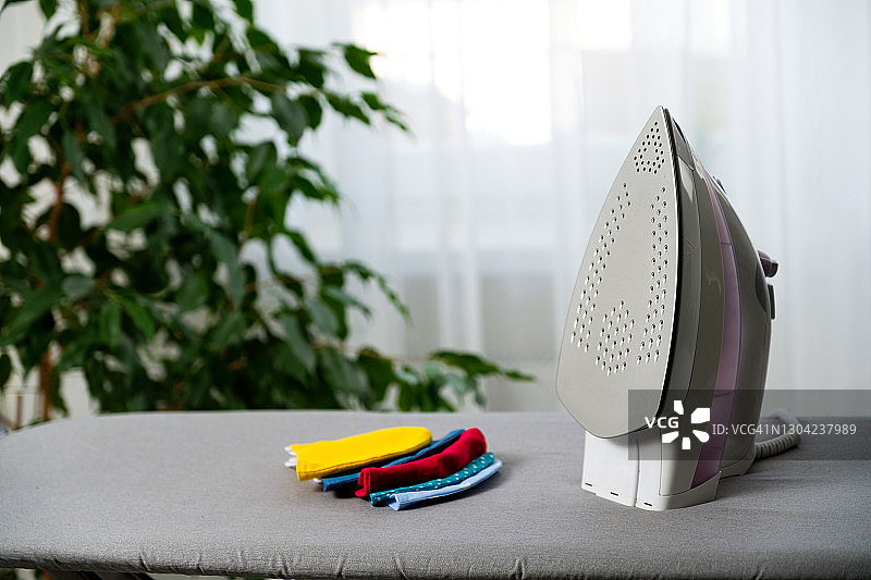 熨衣板上缝制的铁制和可重复使用的布口罩。预防和保护免受流感病毒、COVID-19感染。口罩的消毒和灭菌以供重复使用。图片素材