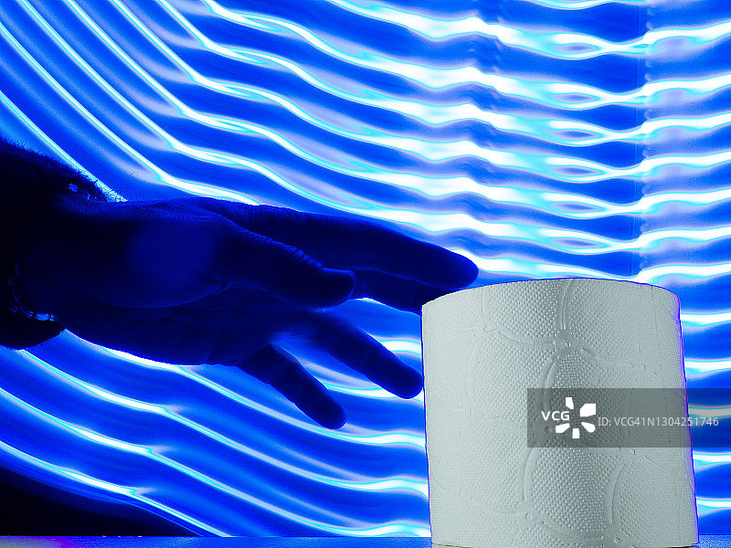 手拿卫生纸卷，背景为未来主义蓝色线条图片素材