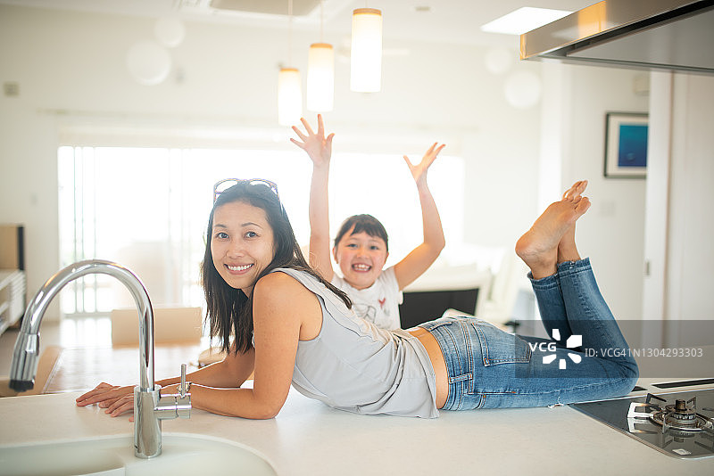 一位快乐的母亲和年幼的女儿躺在厨房长椅上图片素材