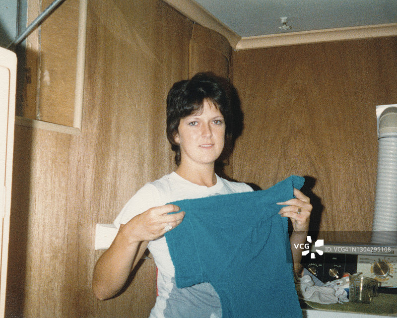 折叠衣服的复古照片，80年代妇女折叠衬衫图片素材