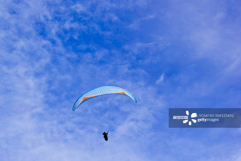 白天的明亮云彩，有游客从山上跳伞图片素材