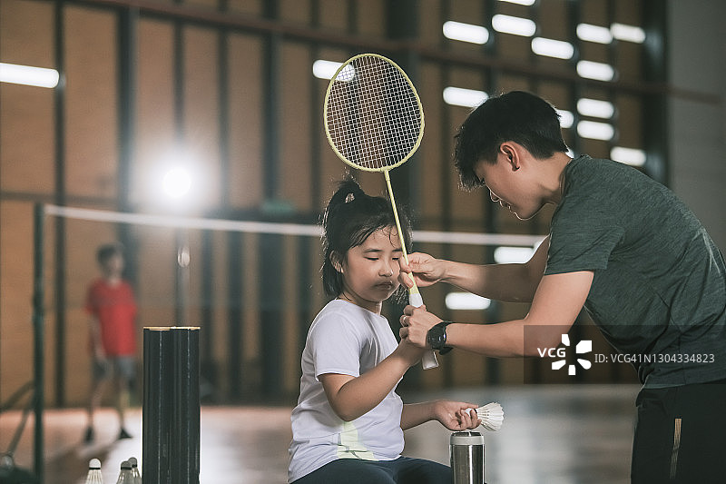 亚洲华人女教练指导学生在羽毛球场准备羽毛球练习图片素材