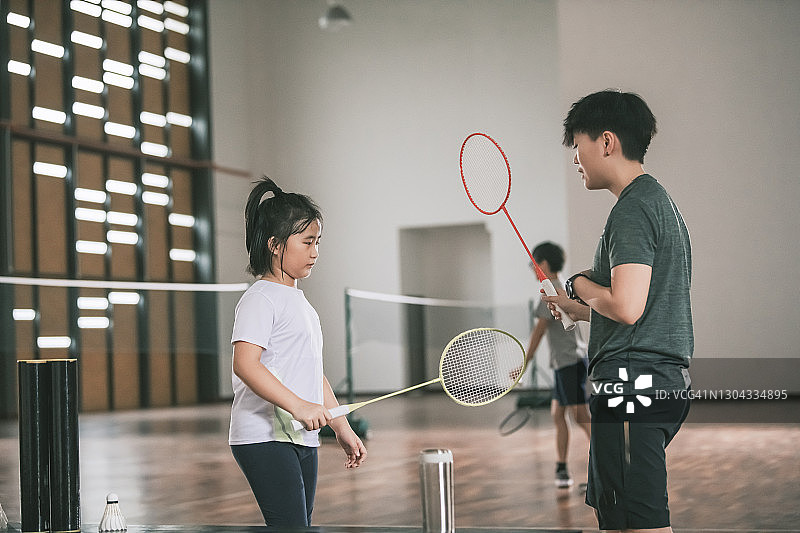 亚洲华人女教练指导学生在羽毛球场准备羽毛球练习图片素材