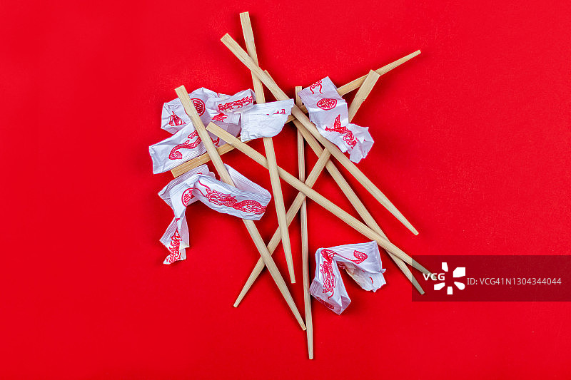 减少浪费：红色背景上堆放着一次性筷子和包装纸图片素材