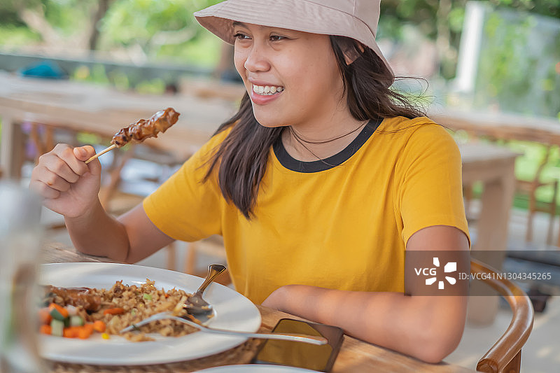 吃鸡肉沙爹和炒饭的年轻印尼女性图片素材