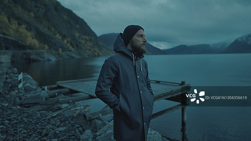 穿着雨衣在峡湾的夜晚的胡须渔夫肖像图片素材