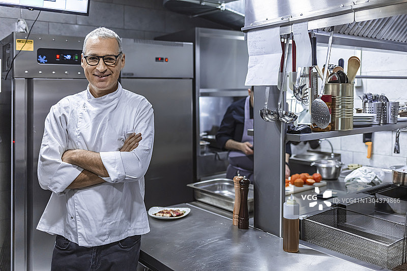 自信的厨师在厨房里双手交叉站立图片素材