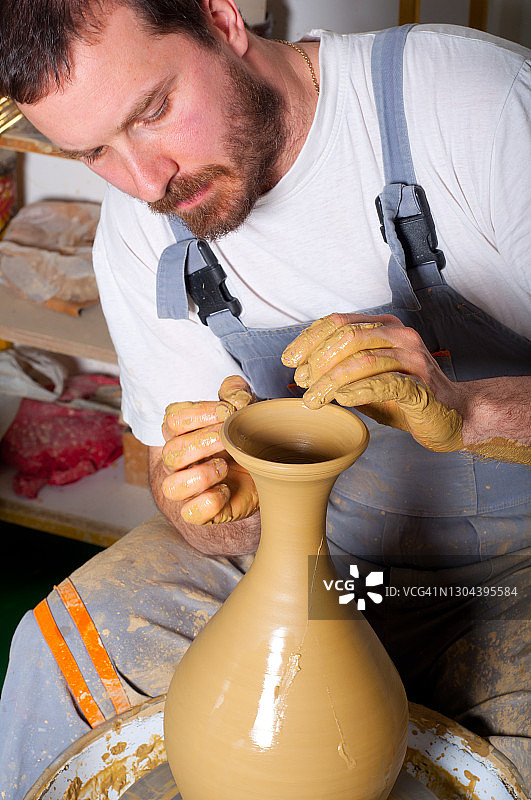 年轻陶艺家在陶轮上制作花瓶图片素材