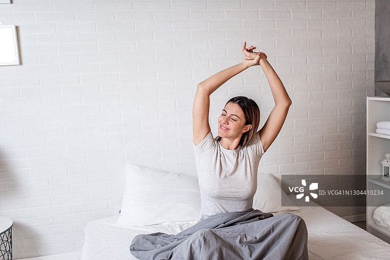 在床上醒来的快乐年轻女人图片素材