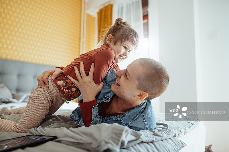 患癌的短发母亲在卧室里和女儿玩耍图片素材