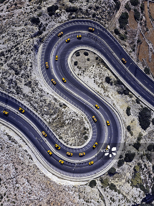 蜿蜒道路上黄色汽车的航拍视角，形似字母S图片素材