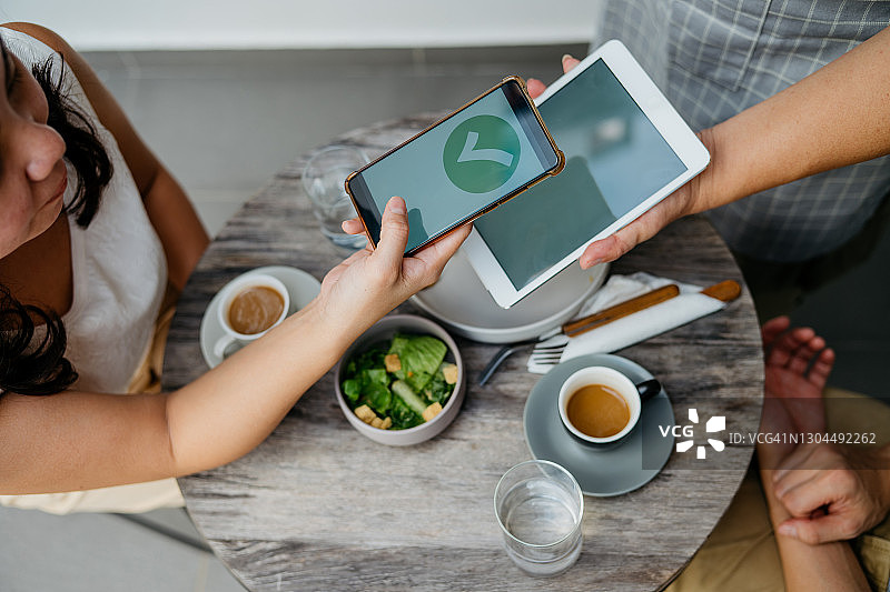 年轻亚裔女性在咖啡馆使用电子钱包支付图片素材