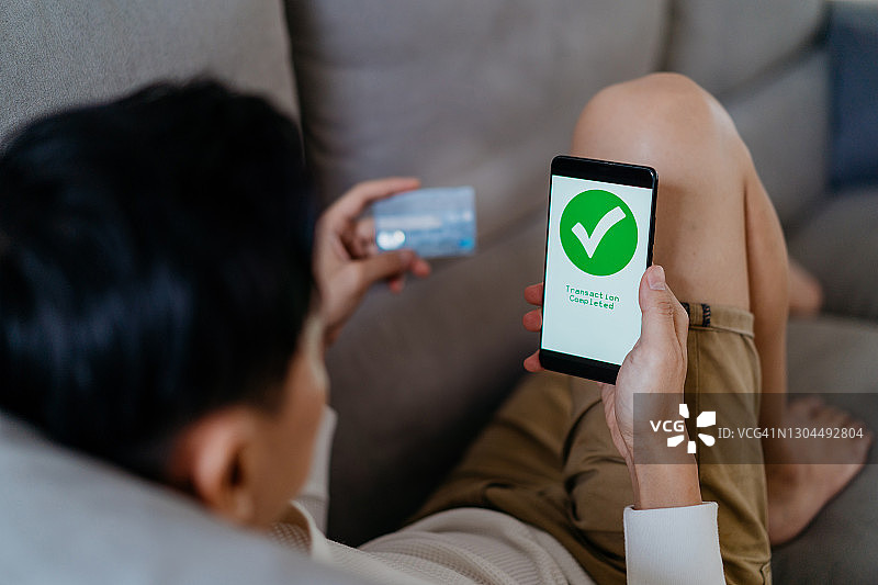 使用智能手机和信用卡进行网上购物的年轻亚洲男人图片素材