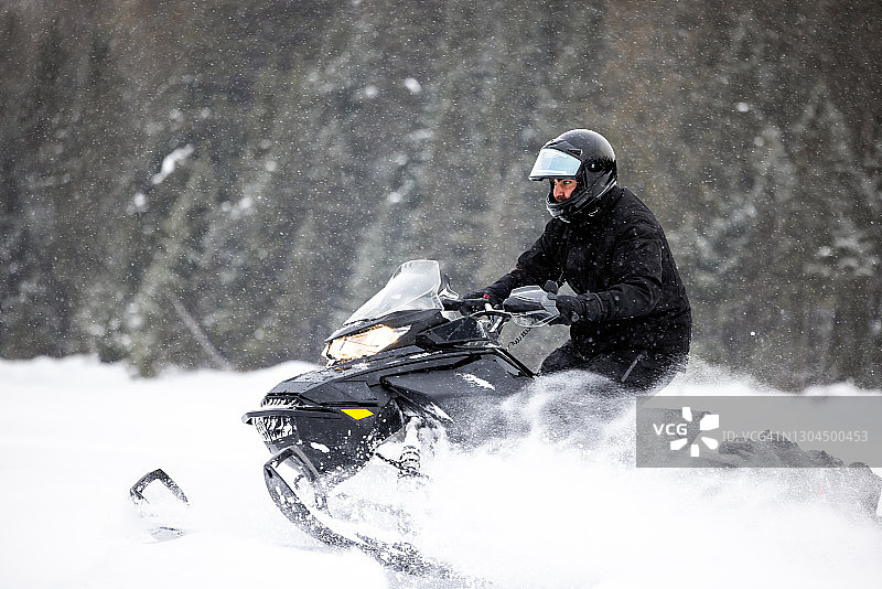 男人开心地驾驶雪地摩托在雪地中飞驰图片素材