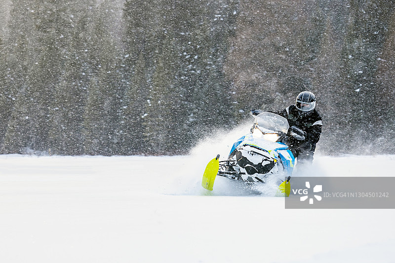 男人在日落时分驾驶雪地摩托在雪地里飞驰图片素材