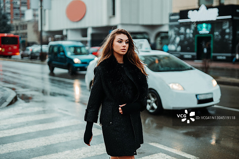 下雪的冬日，年轻女子过马路图片素材