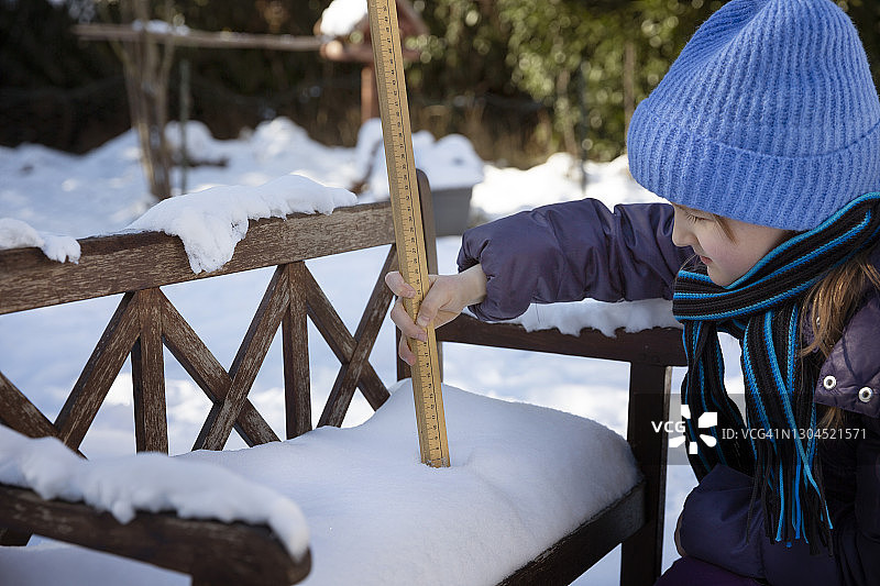 测量后院小长凳积雪深度的孩子（8-9岁）图片素材