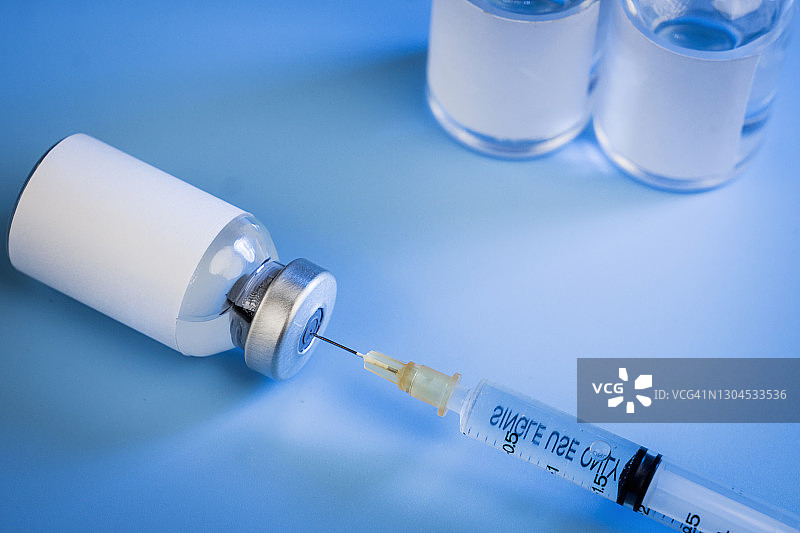 蓝色背景的三瓶玻璃注射器。图片素材