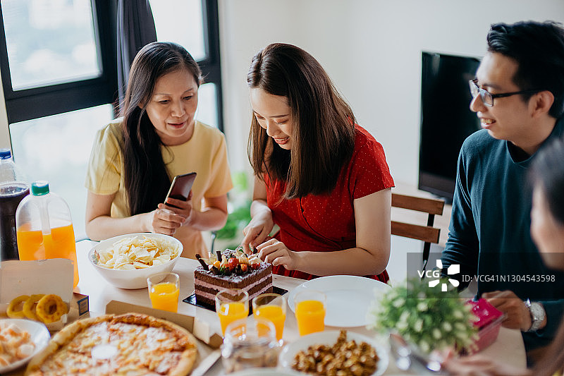 中国亚洲女性在生日聚会上切生日蛋糕图片素材