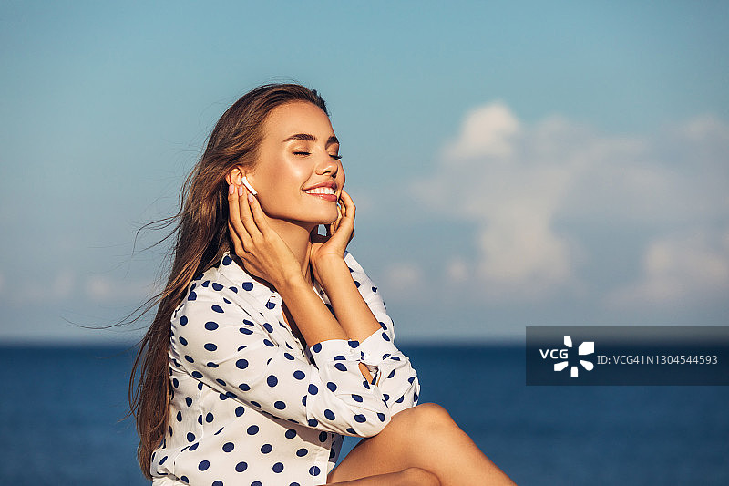 在海滩听音乐的美丽女孩图片素材