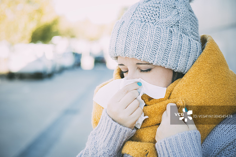 一位穿着冬装的年轻白人妇女擤鼻子的特写图片素材